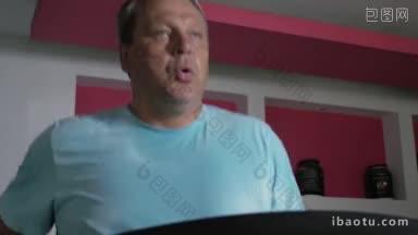 穿着蓝色t恤的成年男子在跑步机上跑步，同时用鼻子呼吸和呼气